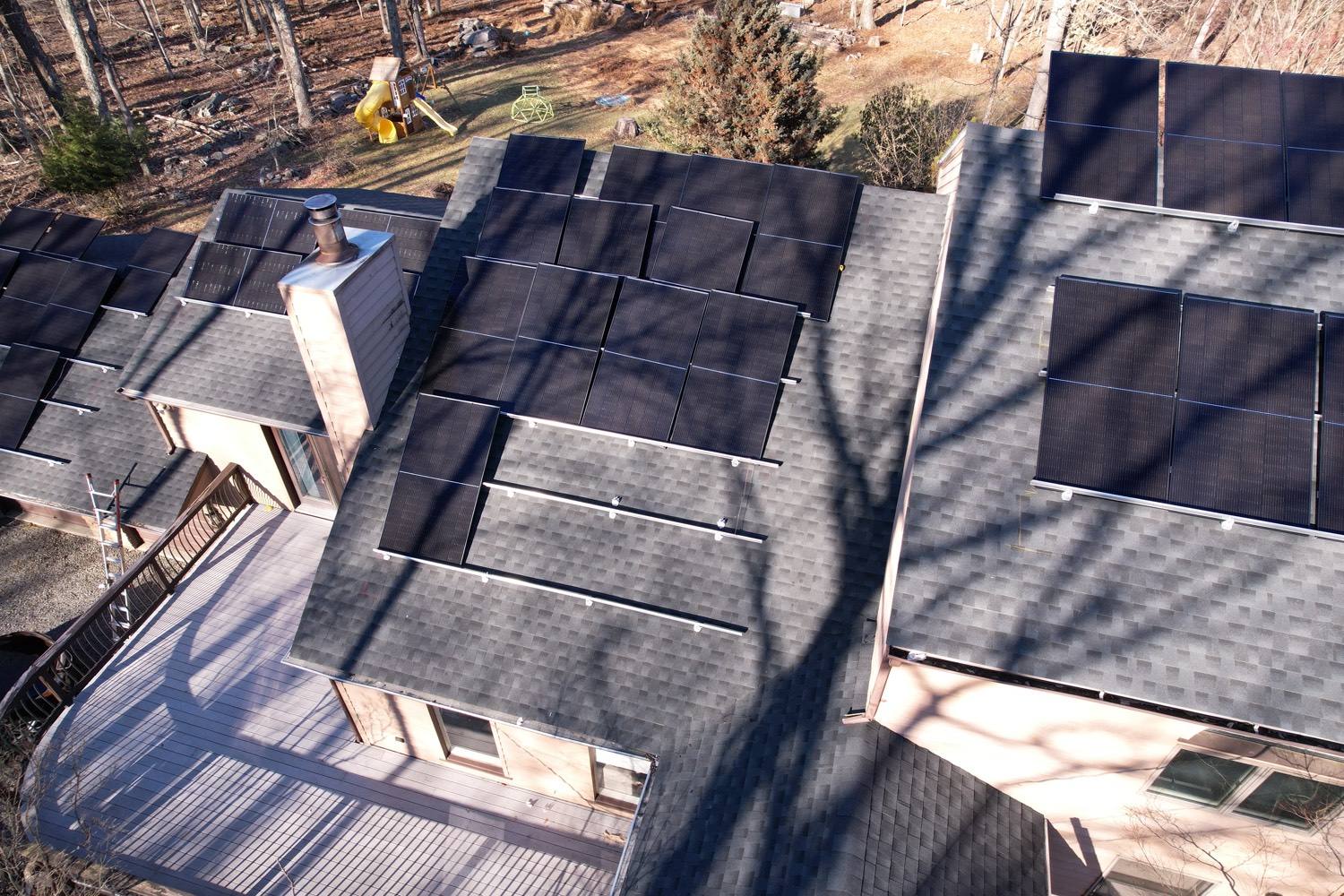 Solar panels installed across several roof faces of a home, viewed from above