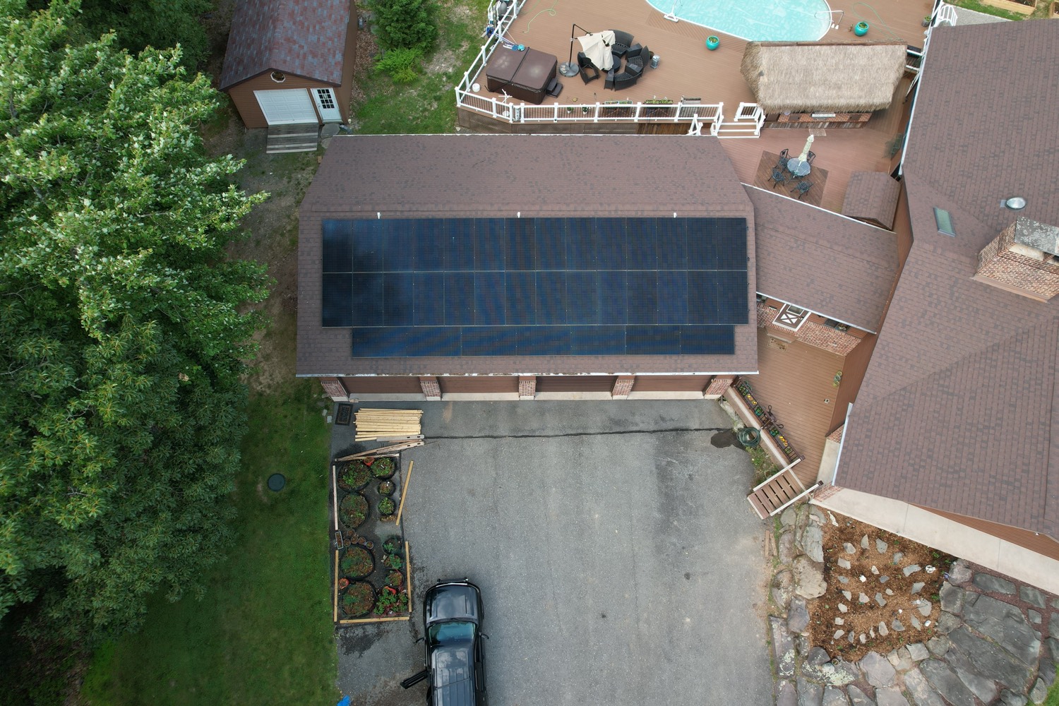 Aerial view of solar panels on a home with a pool and patio in the backyard