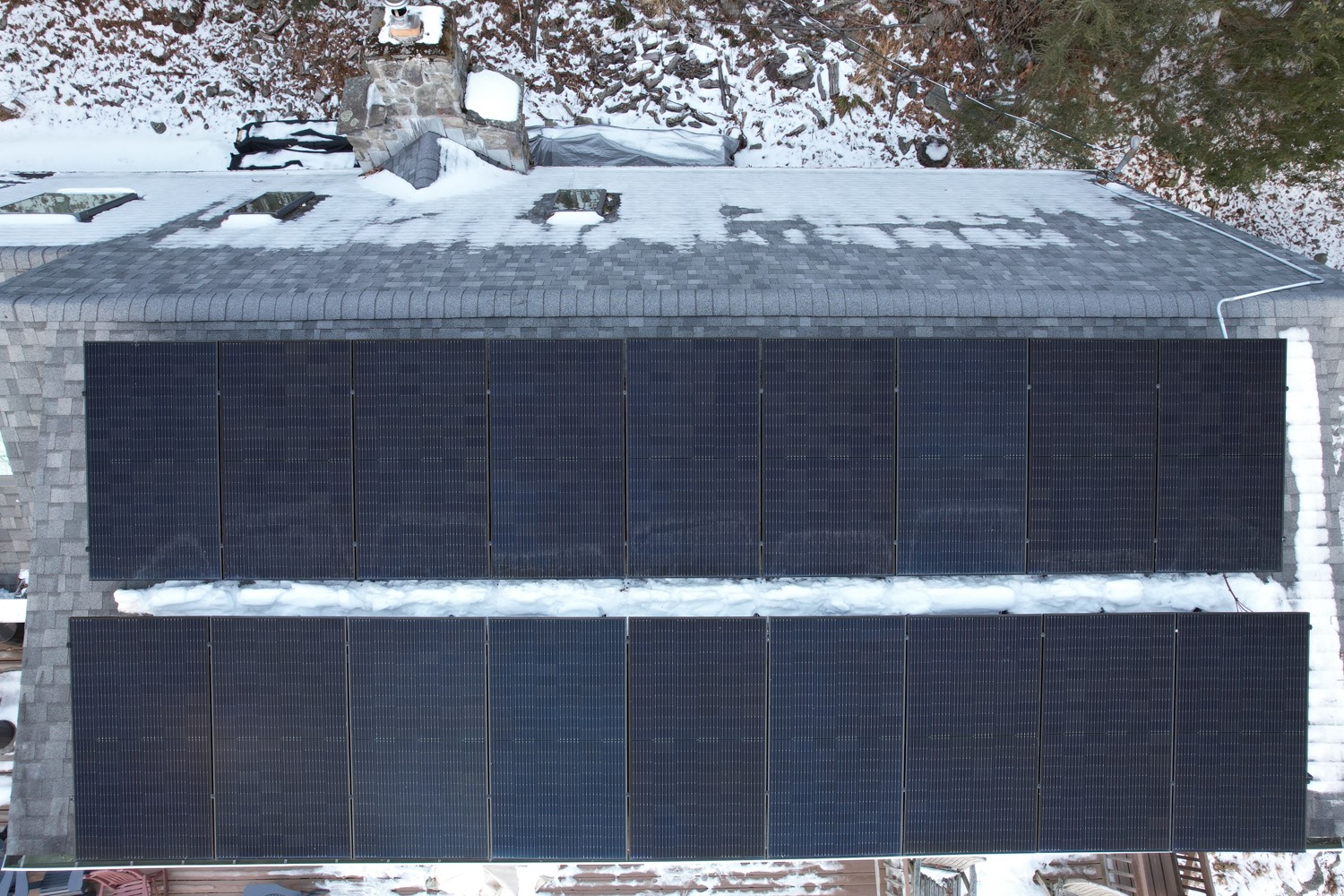 Large two-row solar array on a roof with snow on the surrounding ground